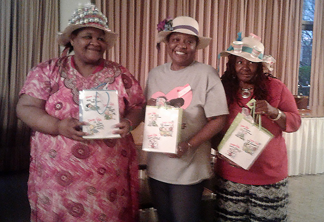 At the Women&rsquo;s Retreat, three winners of the Strawhat Decoration Contest show off their prizes for creating the most beautiful, the most creative and the funniest hats. Photo by Nancy Green.